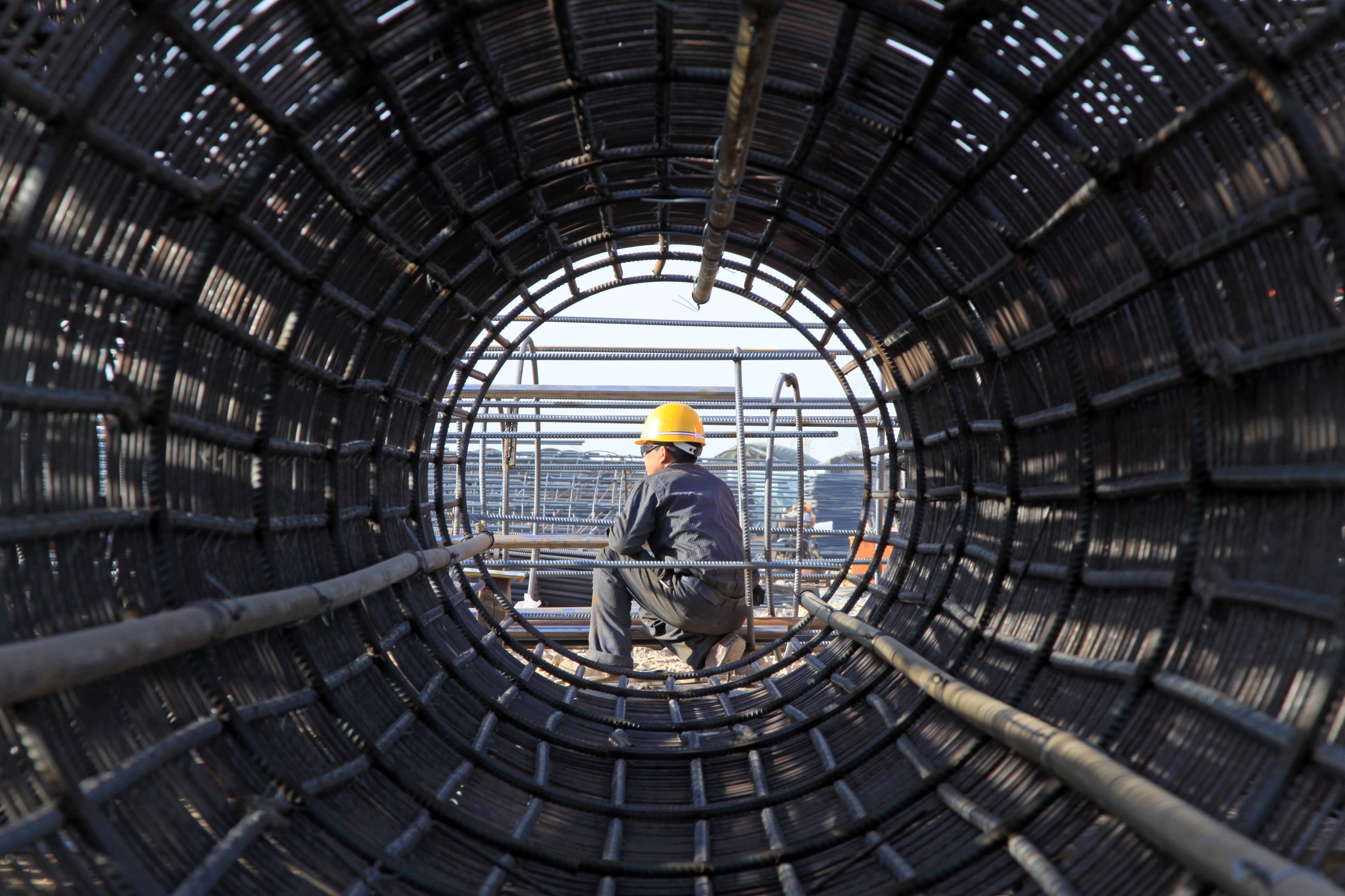 Worker in safety gear examining the interior of a large metal framework tunnel